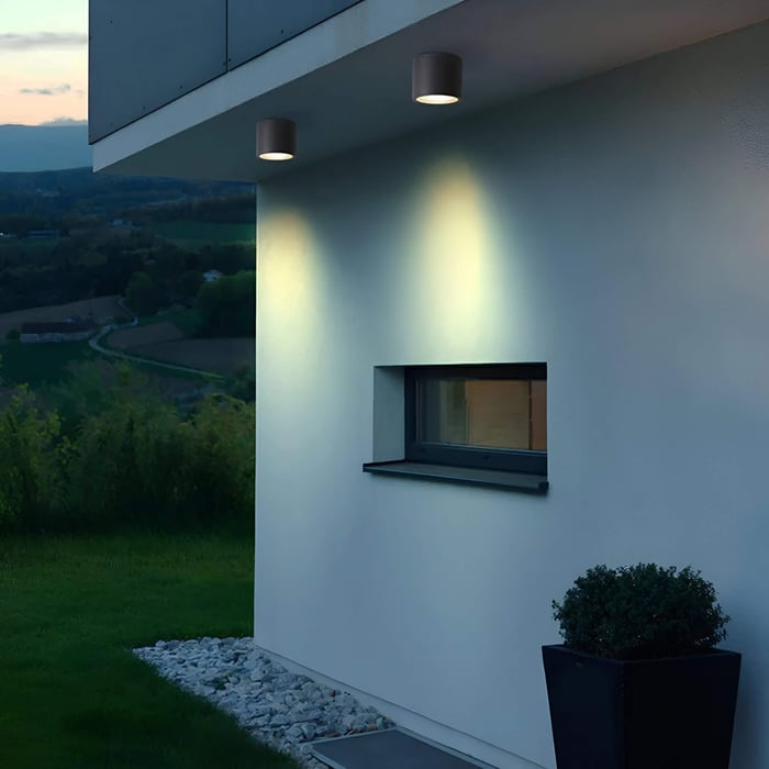 Ceiling-mounted downlights illuminating a white exterior wall at dusk.