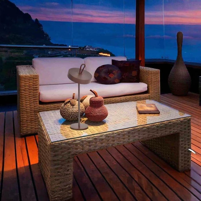 Dimmable Ouutdoor Table Lamps on glass-top rattan coffee table at dusk, coastal balcony lounge with wicker sofa and ocean view.