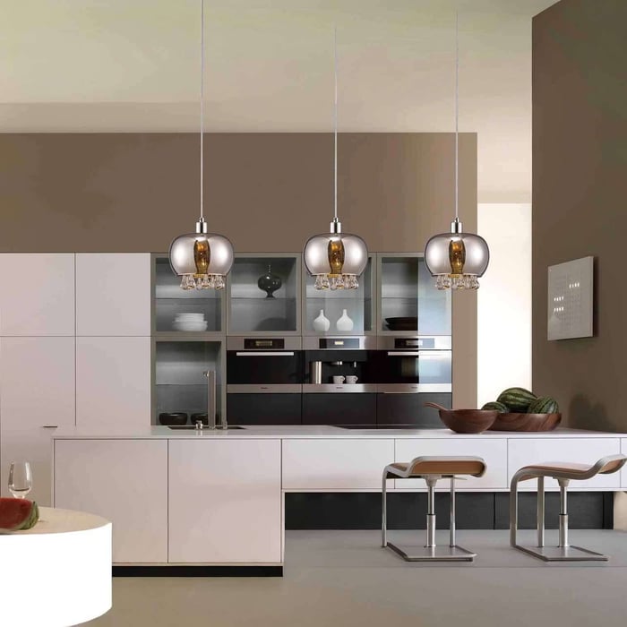 Contemporary kitchen with three chrome-and-glass globe pendants over a white island, paired with beige and white cabinetry.