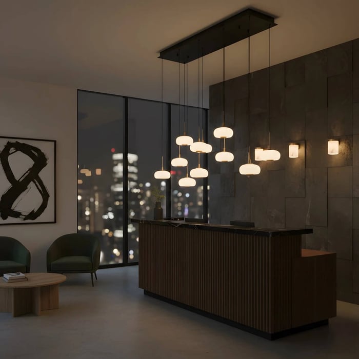 Multiple alabaster pendant lights arranged in a linear cluster above a modern reception desk at night.