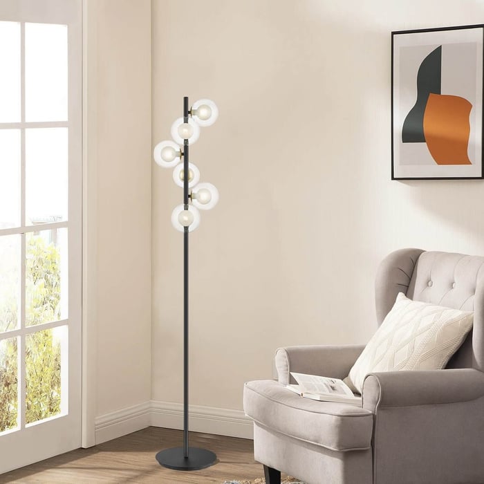Black floor lamp with six glowing ring lights arranged vertically in a cozy corner.