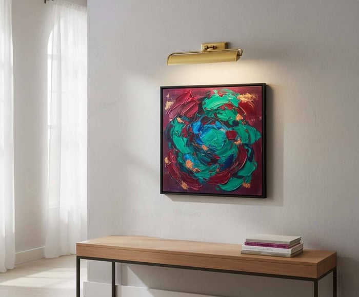 Brass picture light illuminating a bold teal-and-red abstract painting above a minimalist wood console in a sunlit room.