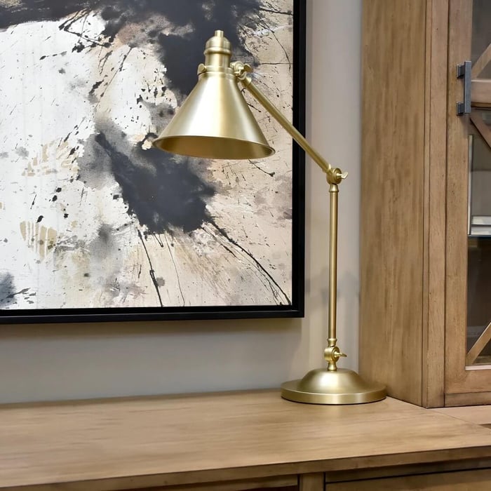 Brass desk lamp beside a vintage typewriter and books on a wooden table