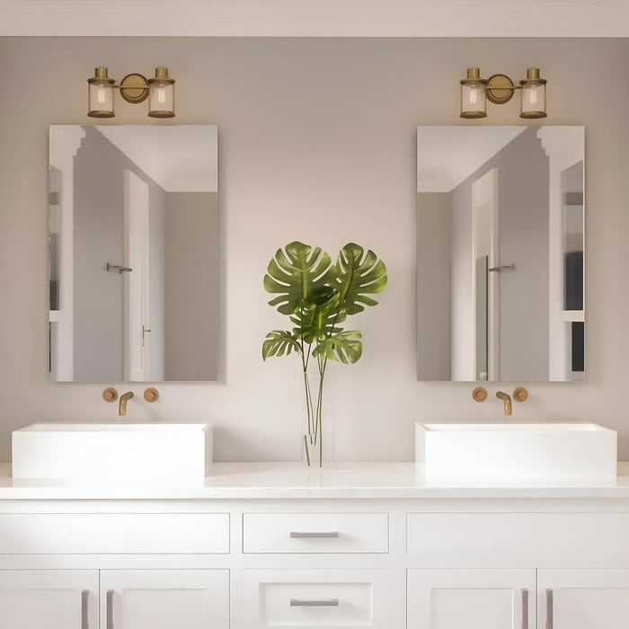 Elegant vanity with dual square sinks, gold hardware, and soft lighting, accented by a leafy green plant between mirrors.