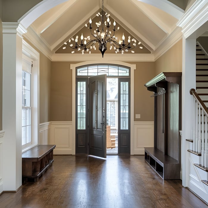 Modern black chandelier with leaf-shaped lights in a tall entryway with vaulted ceiling.