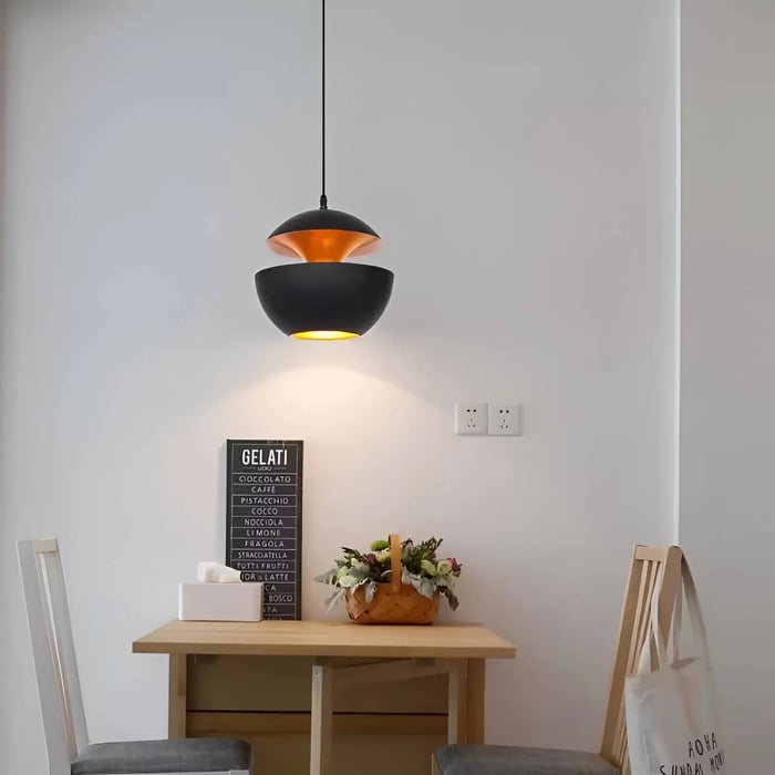 Minimalist black and copper pendant dining room light above compact dining table.