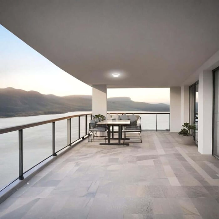 Covered terrace with a single recessed ceiling light above an outdoor dining set overlooking water.