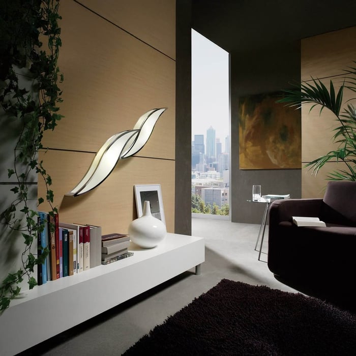 Contemporary room with wave-shaped LED wall light, bookshelf, and city view.