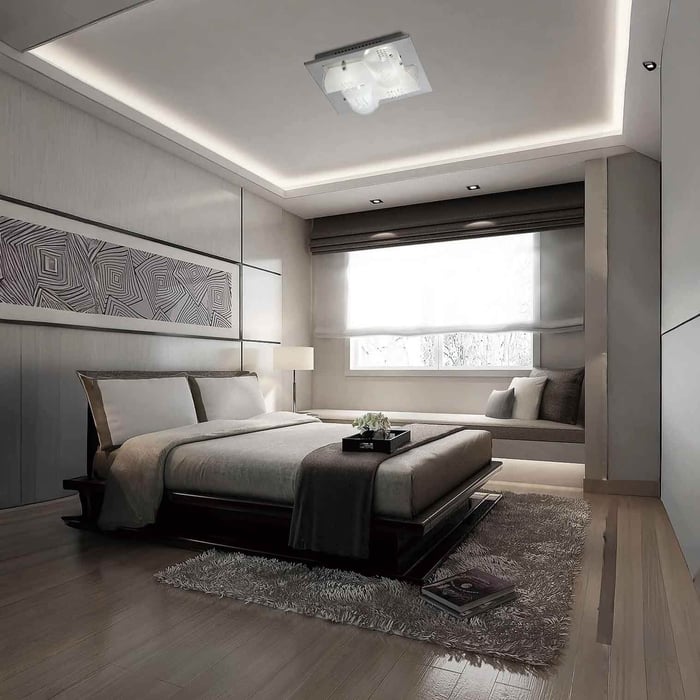 Contemporary bedroom with a square glass ceiling light and soft cove lighting around the perimeter.