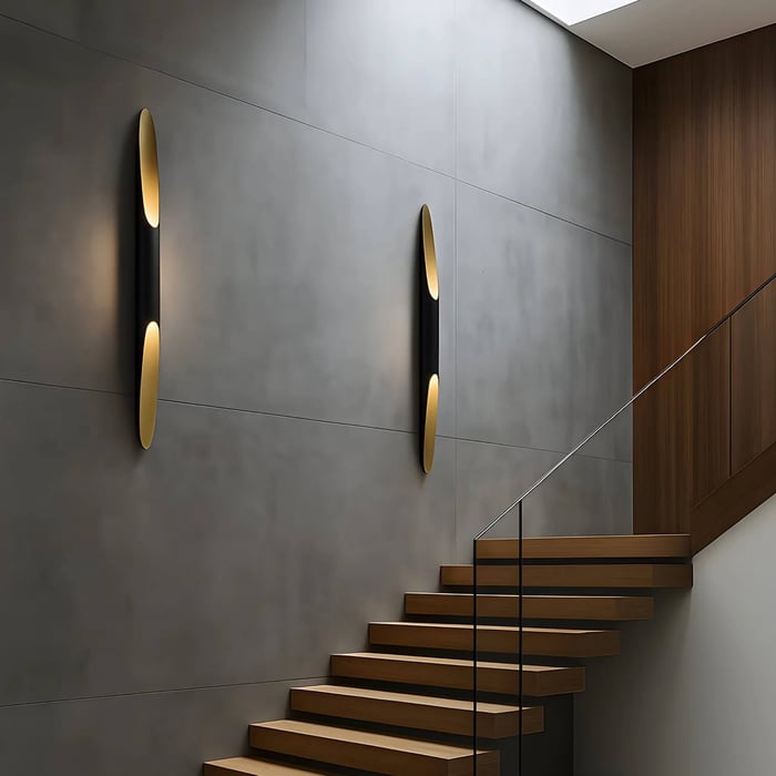 Modern staircase with floating wooden steps and two sleek black-and-gold wall sconces on a smooth gray wall, creating a minimalist contemporary look.
