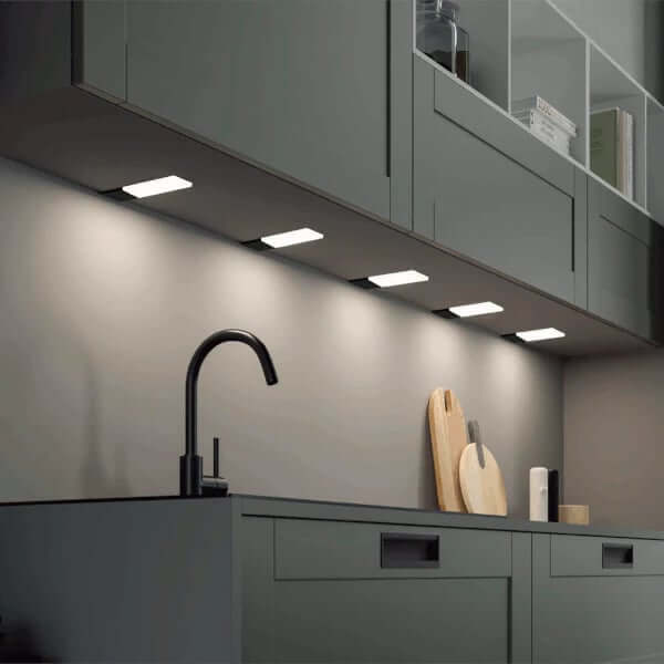 Grey kitchen with under-cabinet square lights illuminating the worktop and splashback.
