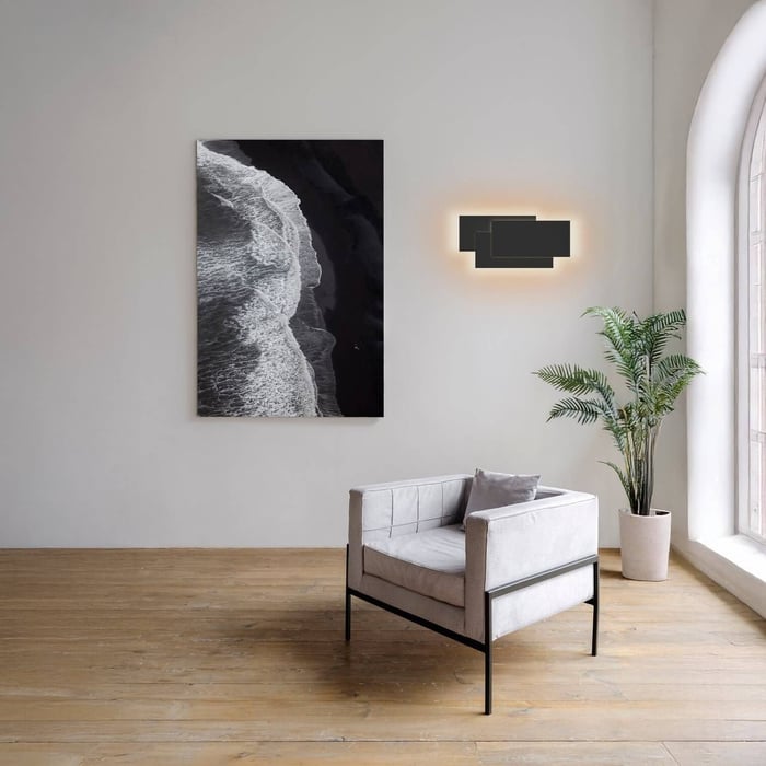 Minimal room with gray armchair, abstract wall art, and rectangular modern wall light.
