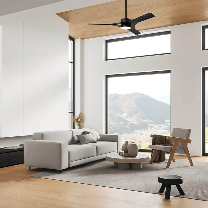 Modern living room with large windows, light wood ceiling, neutral furniture, and a black ceiling fan light centered above the seating area.
