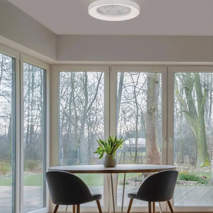 Dining nook with round table under a flush ceiling fan light and large glass doors to the garden.