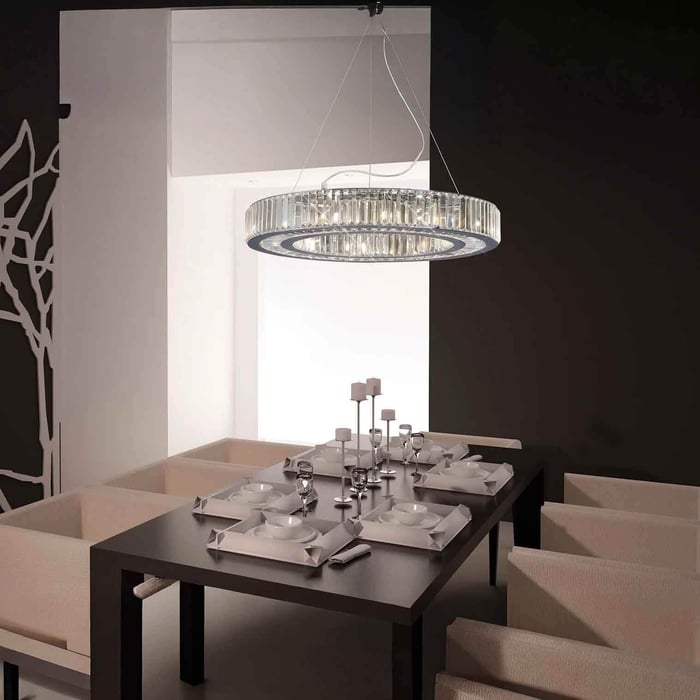 ow-profile circular crystal pendant light above a dining table in a dark, modern dining room.