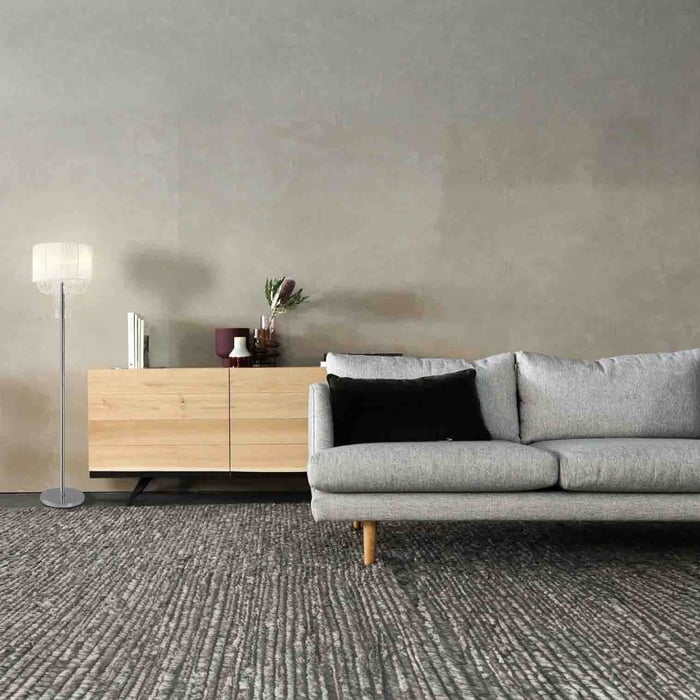 Minimalist room with chrome traditional floor lamp, sheer drum shade, light wood credenza, and gray sofa.