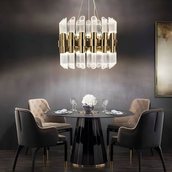 Gold and clear glass chandelier above a round dining table in a dark, modern dining room. MagariLEDSuspensionLight-Gold-location
