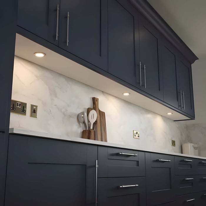 Modern kitchen with small under-cabinet spotlights washing light over a marble-effect backsplash.