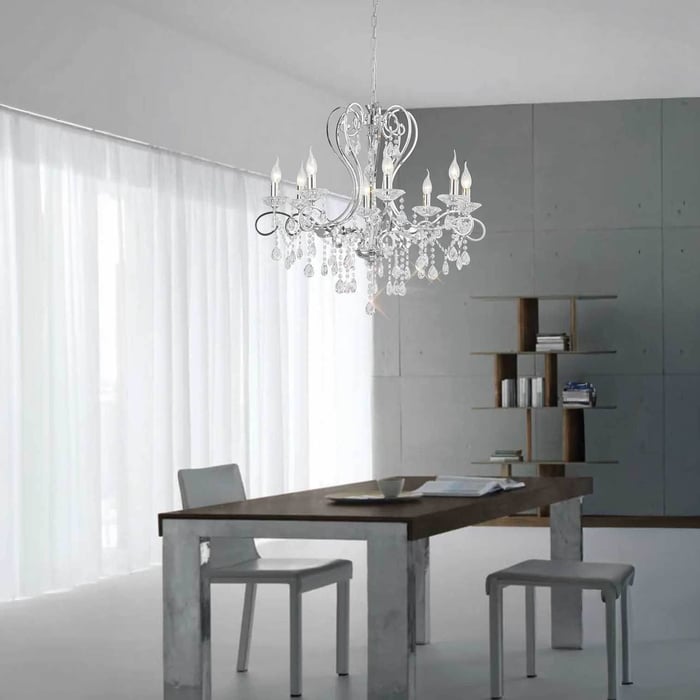 Traditional clear crystal chandeliers hanging in a minimalist room with sheer curtains and grey walls.