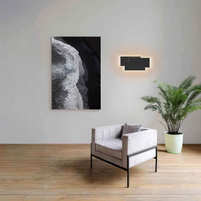 Modern loft interior with wooden staircase, tall windows, and a small wall sconce adding soft light to the open space.