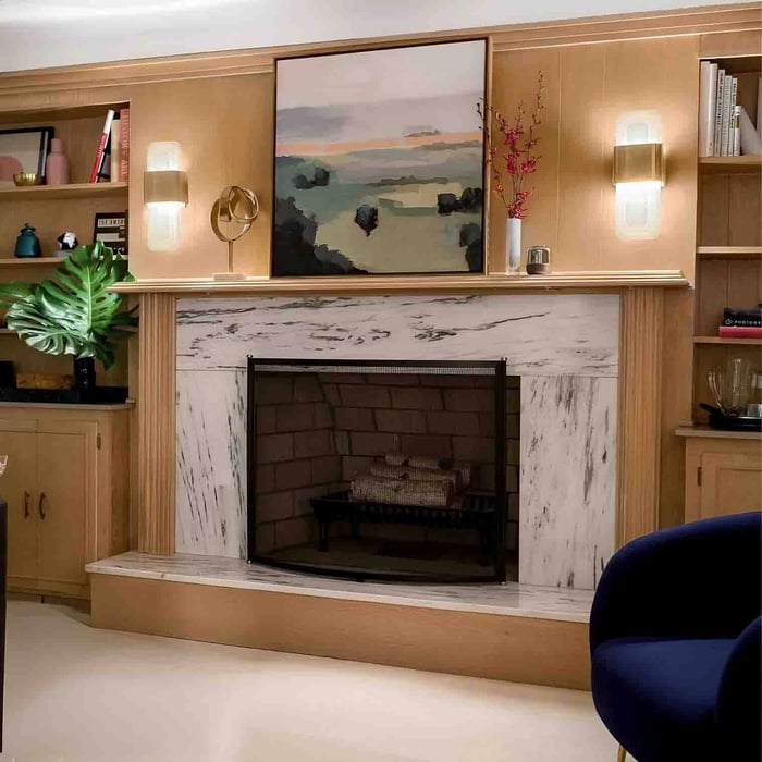 Living room with marble fireplace, built-in shelves, and two brass-and-glass wall lights flanking the mantel.
