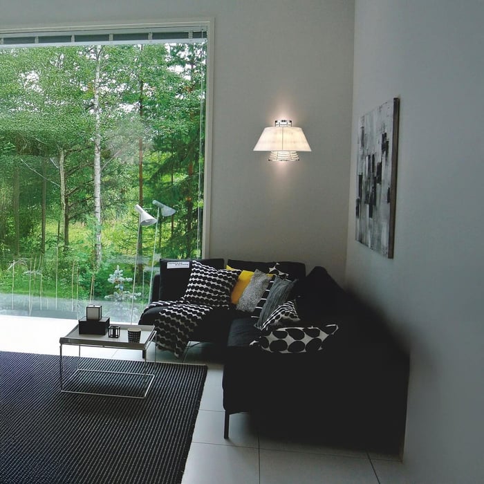 Modern living room with large window, black sofa, and wall lamp with white shade.