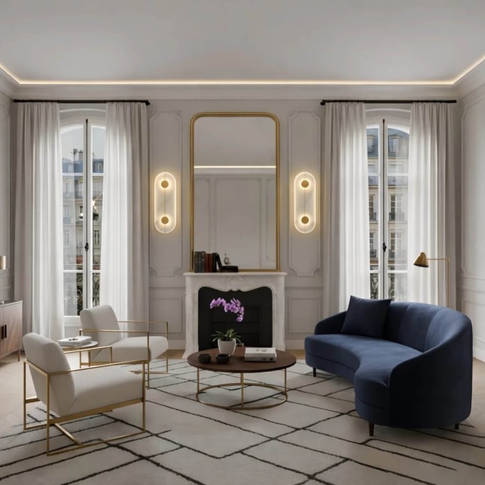 Elegant Parisian-style living room with ornate molding and tall windows, featuring two oval wall sconces flanking a gold-framed mirror above a fireplace.