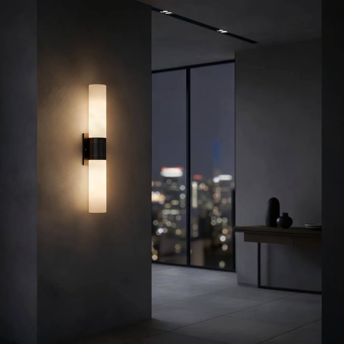 Contemporary hallway at night with city skyline view, featuring a double-ended wall sconce casting warm light on a textured wall.