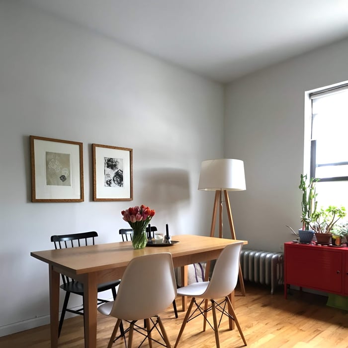 Minimalist floor lamp with tripod base lighting a cozy dining nook with tulips.