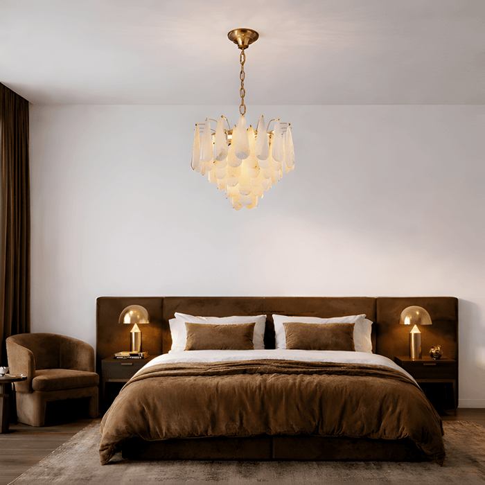 Elegant bedroom with a tiered alabaster chandelier hanging above a brown upholstered bed and matching bedside lamps.
