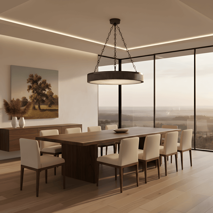 Modern dining room with large circular chandelier suspended by chains above wooden table, upholstered chairs, and floor-to-ceiling windows overlooking countryside view.
