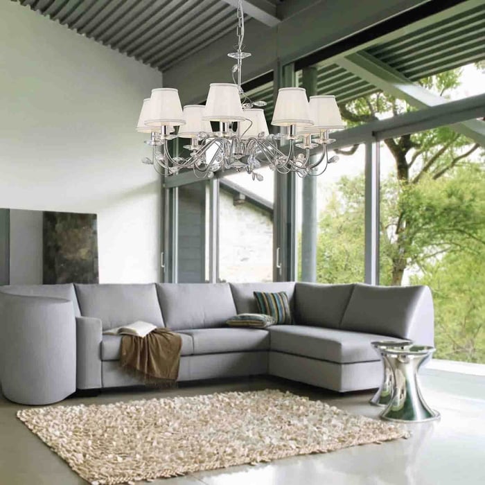 Traditional chandelier with fabric shades hanging in a modern living space featuring large windows, a sectional sofa, and natural textures.