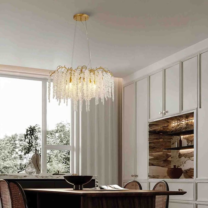 Gold and crystal fringe chandelier hanging above a modern dining table beside a large window.