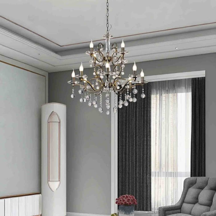 Traditional multi-arm crystal chandelier with gold accents hanging in a classic living room with soft grey walls and elegant curtains.
