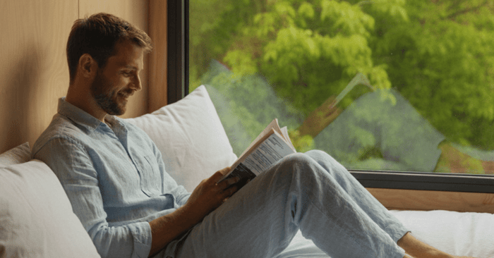 Man reading in bed with natural light, showing comfortable rest compared to overheating under down alternative bedding | Antipodean Home