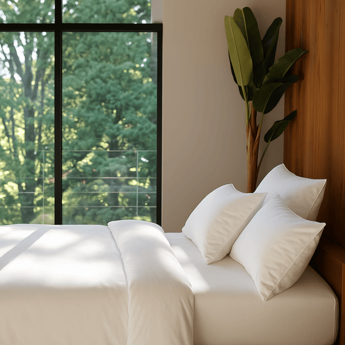 Modern bedroom with white sheets and pillows illustrating how cooling bedding keeps sleepers comfortable in warm conditions.