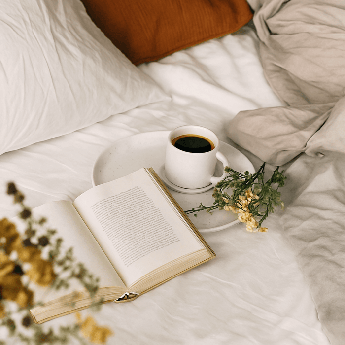 Woman waking up refreshed in bed, stretching comfortably under breathable bedding made from natural fibers like regenerative wool and organic cotton.