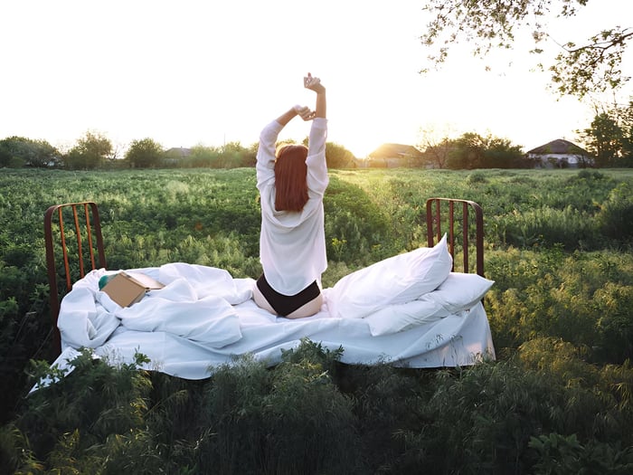 Woman stretching on organic comforter and wool bedding in a field, symbolizing deep restorative sleep