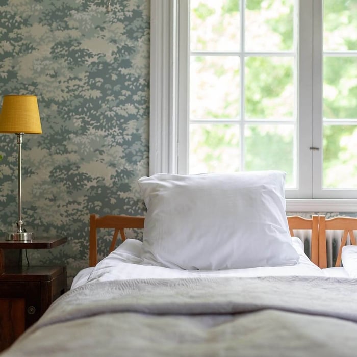 Wool vs bamboo duvets comparison – minimalist bedroom with white wool bedding on wooden frame, showing breathable natural materials for cooler sleep