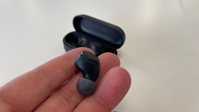 Sony WF-C510 earbuds held in hand against white background