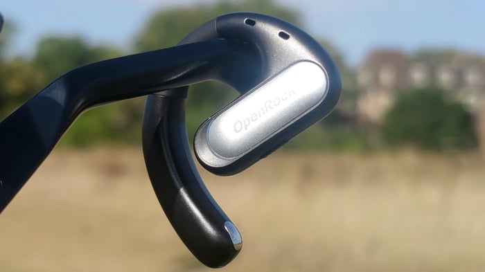 OpenRock Pro earbuds hanging off a bike brake, showcasing their sporty design.
