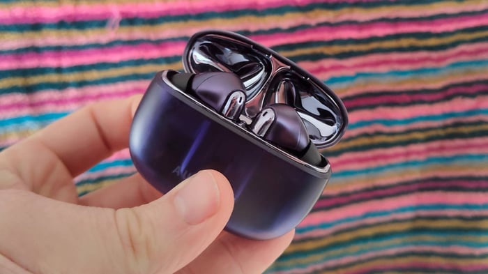 Creative Aurvana Ace 3 earbuds and case in front of colorful striped screen