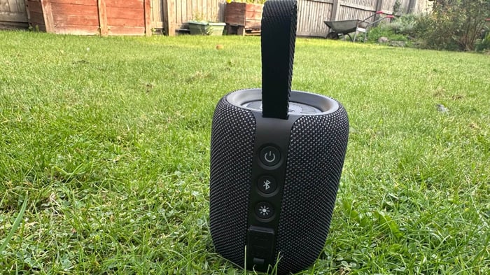 Rear view highlighting buttons and connectivity ports, set against a lush green backdrop.