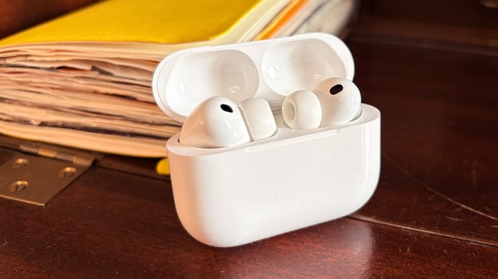 AirPods Pro 3 in open case resting on a wooden desk