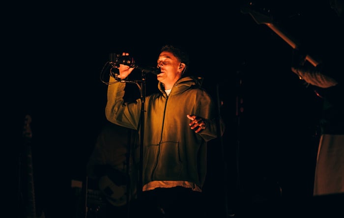 An emotional Loyle Carner sits on the edge of the stage during his set