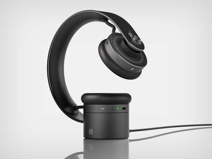 Hand pressing the signature B&O dot on the headphone