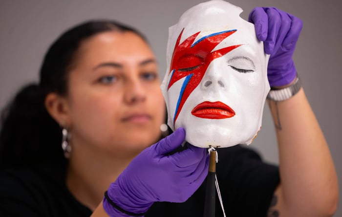 A V&A Collections Access Officer handles a life mask of David Bowie’s face painted as Aladdin Sane