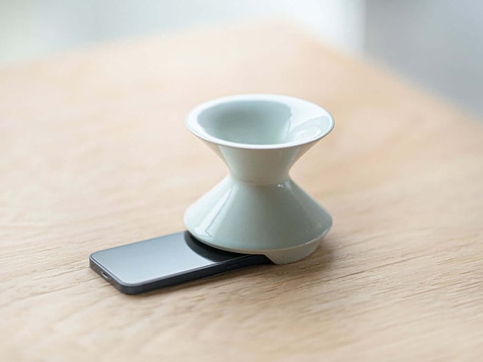 Ceramic vase doubling as a phone speaker on a wooden table