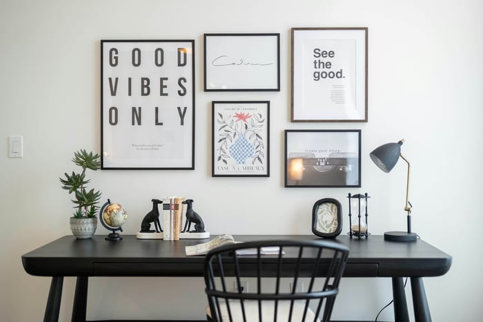 Framed typography and botanical posters arranged above a home-office desk