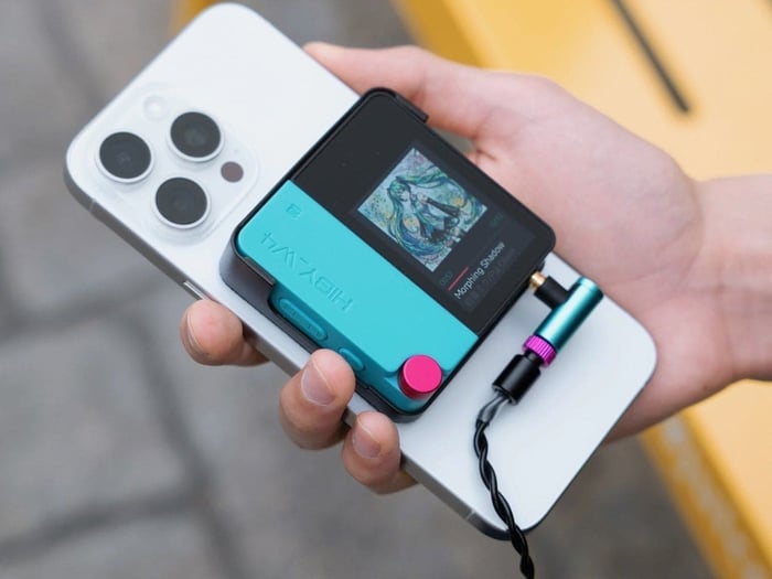 HiBy W4 portable amplifier positioned alongside a smartphone